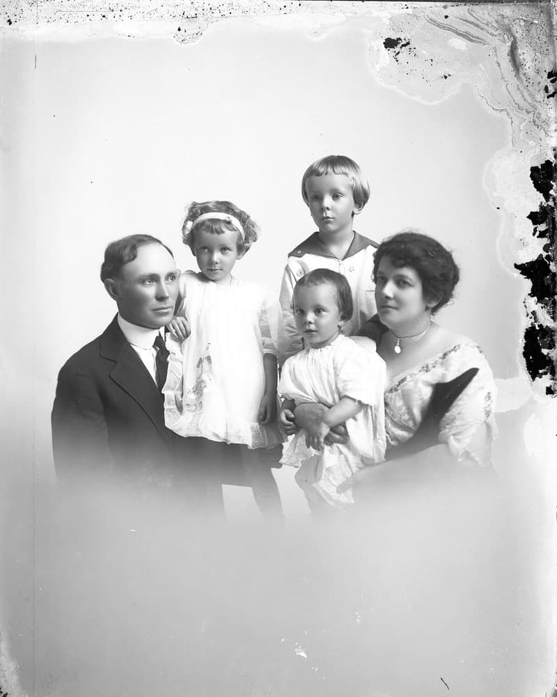 Original glass-plate family portrait of parents with three children, with damaged emulsion along the edges
